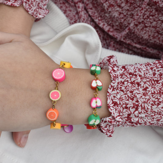 Multicolor charm bracelet with apple-shaped beads and gold-tone links, worn on wrist